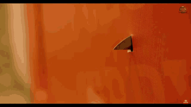 a knife is sticking out of a hole in a red wall with the sun written on the bottom