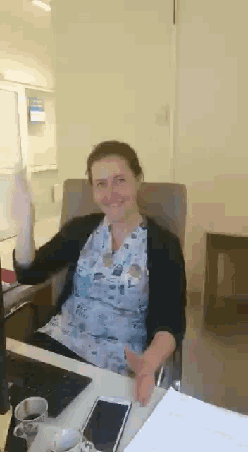 a woman is sitting at a desk with a laptop and a phone .