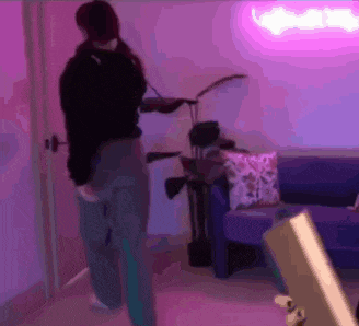 a person is standing in a room with a couch and a neon sign .