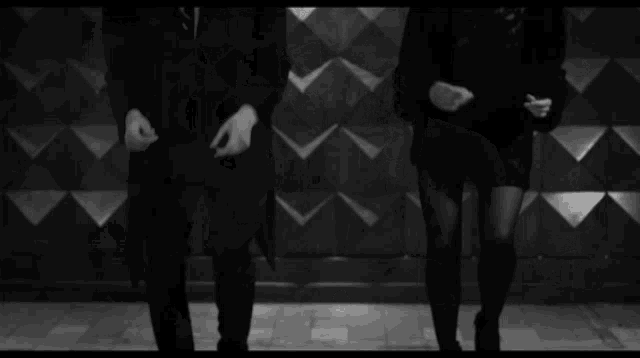 a black and white photo of a person 's feet walking on a tiled floor