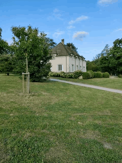 a white house sits in the middle of a grassy field
