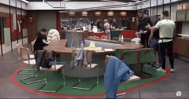a group of people are standing around a table in a room with a green circle in the middle
