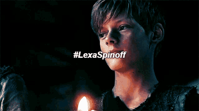 a close up of a person holding a lit candle with #lexaspinoff written on the bottom