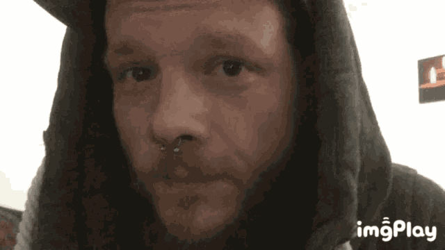 a man with a beard wearing a hoodie and a nose ring .