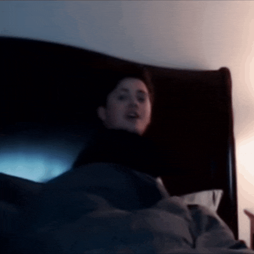 a person laying in bed with a blanket on their head