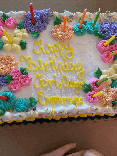 a birthday cake with flowers and candles that says happy birthday lori
