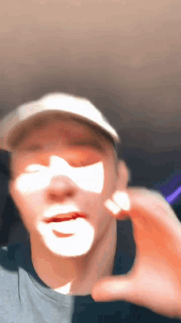 a man wearing a hat and a gray shirt is making a funny face