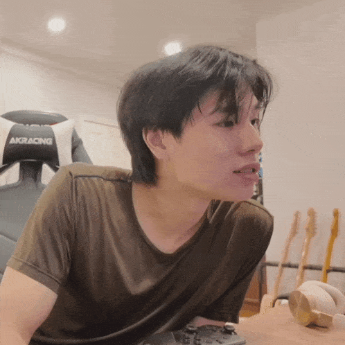 a man sitting at a table with a akracing chair in the background