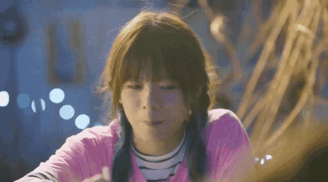a girl with pigtails is wearing a pink shirt and striped shirt .