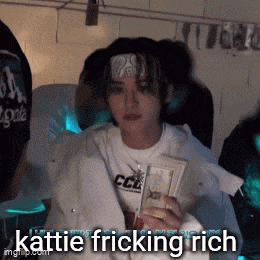 a woman with a bandana on her head is holding a bunch of money and says kattle fricking rich