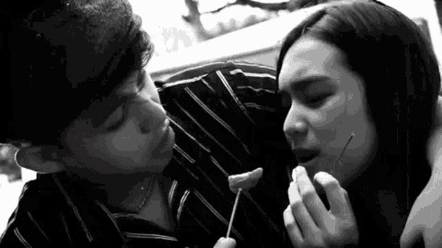 a black and white photo of a man and woman eating food .