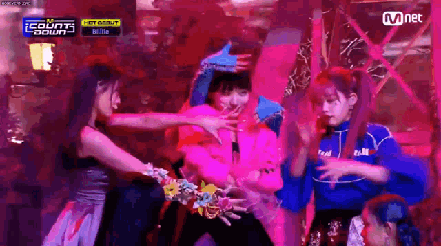 a group of young women are dancing on a stage in a dark room .