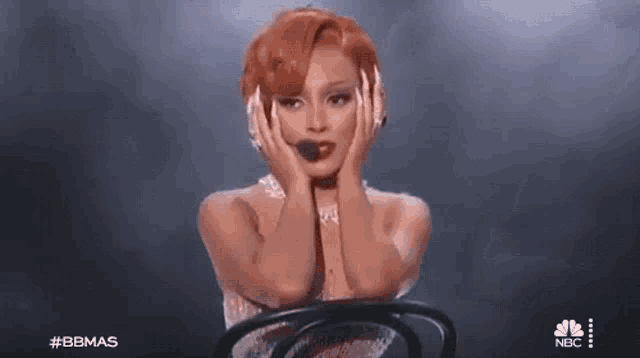 a woman with red hair is sitting in a chair on a stage .