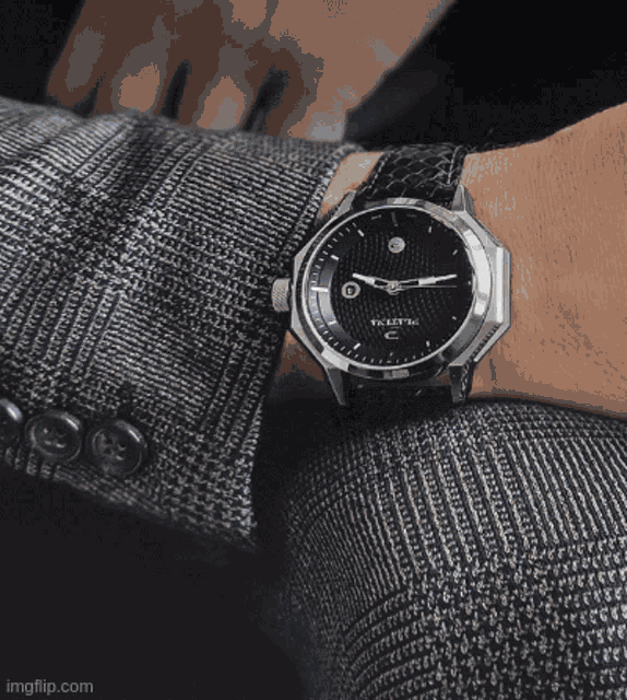 a man is wearing a watch that says ' t.k.e.i.t.e.c. ' on the face