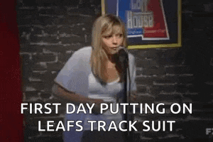 a woman is standing in front of a microphone with the words `` first day putting on leafs track suit '' written below her .