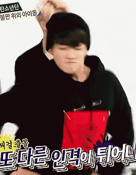 a man in a black hoodie is holding a red bag with chinese writing on it .