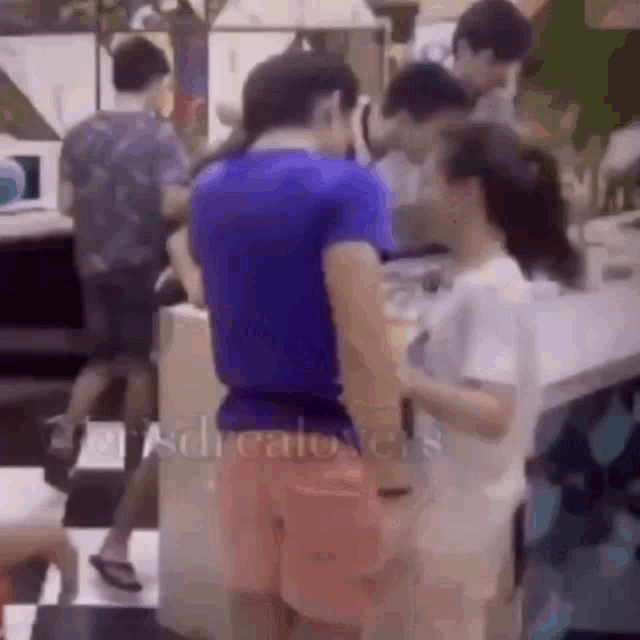 a man in a blue shirt is standing next to a woman in pink shorts .