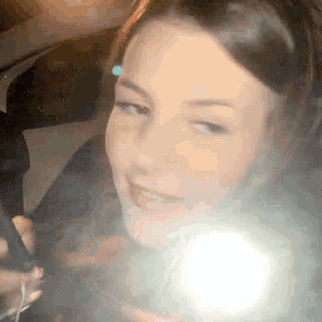 a woman is taking a picture of herself in a car with her phone .