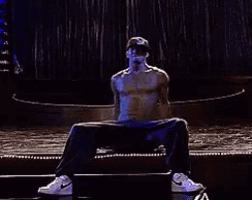 a man without a shirt is dancing on a stage .