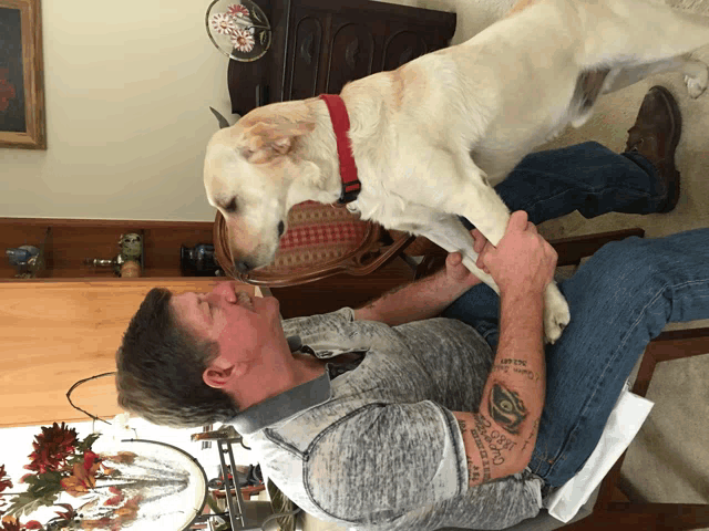 a man with a tattoo on his arm holds a dog 's paw