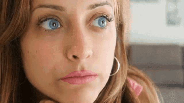 a close up of a woman 's face with blue eyes and pink lipstick .