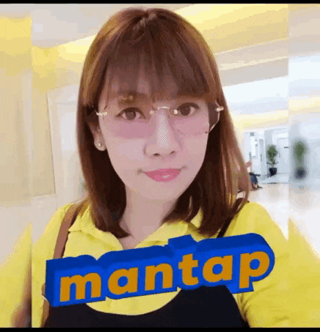 a woman wearing glasses and a yellow shirt with the word mantap written on it