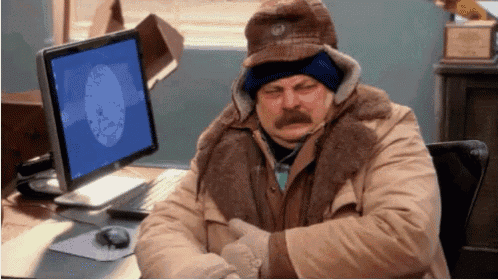 a man sitting in front of a computer wearing a hat and gloves