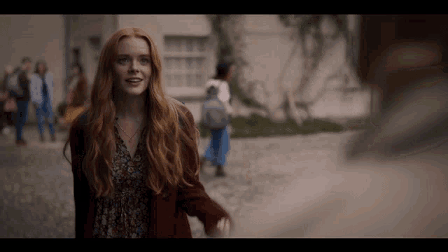 a woman with red hair wearing a red cardigan