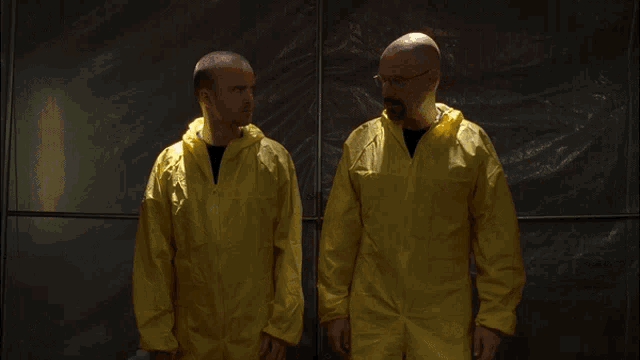 two men standing next to each other wearing yellow jackets