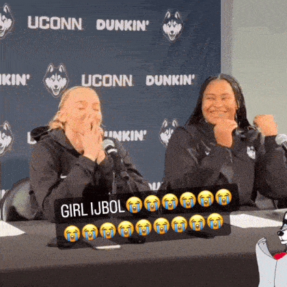 two women are sitting at a table with a sign that says girl ijbol on it