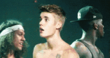 a man in a ny hat is standing next to a shirtless man .