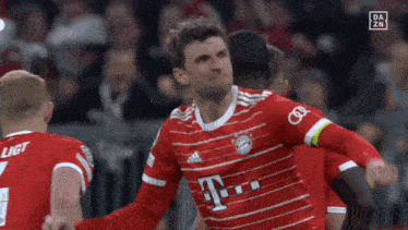 a soccer player wearing a red shirt with the letter t on the front