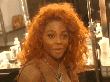 a woman with red hair and a necklace is looking at the camera