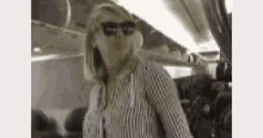 a woman wearing sunglasses and a plaid shirt is standing on an airplane .