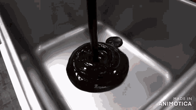 a black liquid is being poured into a sink and the words made in animotica are on the bottom