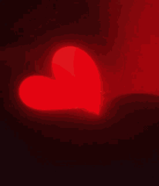 a red heart is glowing on a black background