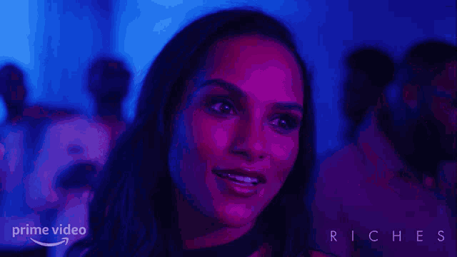 a woman in a dark room with a blue light behind her that says prime video riches