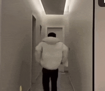 a man is walking down a hallway in a white jacket .