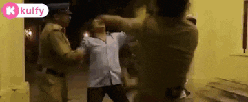 a group of police officers are standing next to each other and fighting a man .