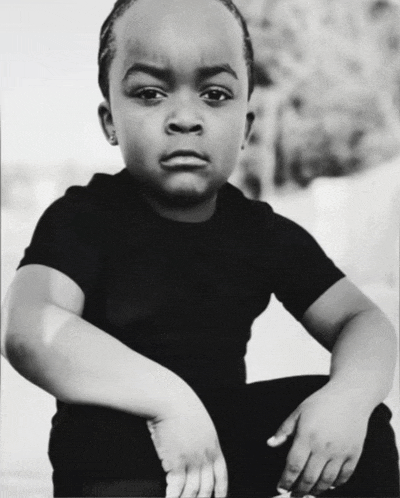 a black and white photo of a young boy wearing a black t-shirt