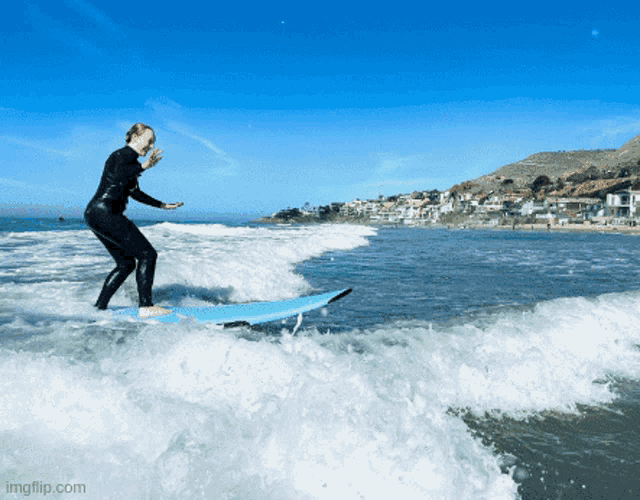 a woman in a wetsuit is riding a wave on a surfboard with imgflip.com at the bottom