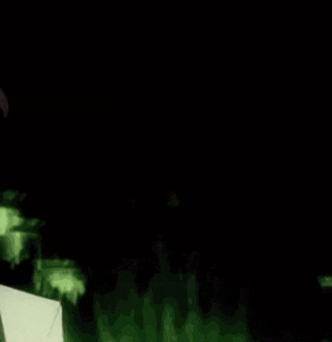 a girl with pink hair is standing next to a man in a dark room .