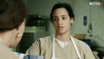 a woman in an apron is talking to another woman in a room .