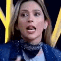 a close up of a woman 's face with her mouth open and a blue jacket on .