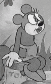 a black and white cartoon of a mickey mouse sitting on a rock .