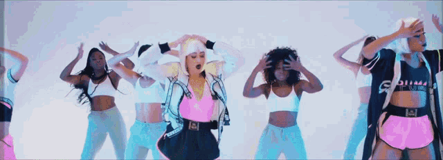a woman in a pink top with the letter a on it is surrounded by other women