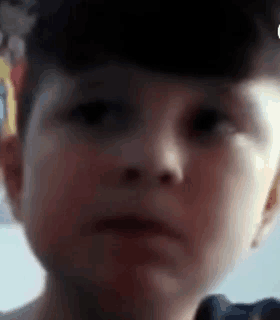 a close up of a young boy making a funny face .