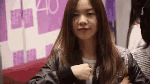 a woman in a black jacket is sitting on a red couch and smiling .
