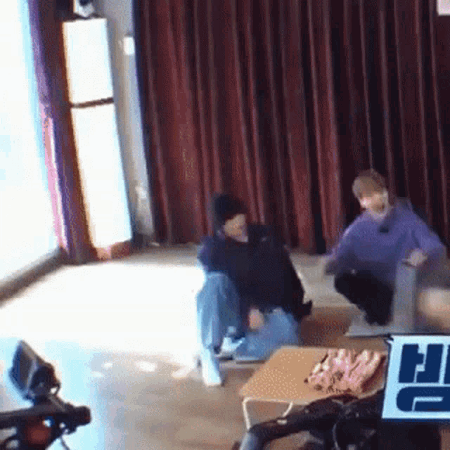 a couple of people are sitting on the floor in a room with a sign that says hi