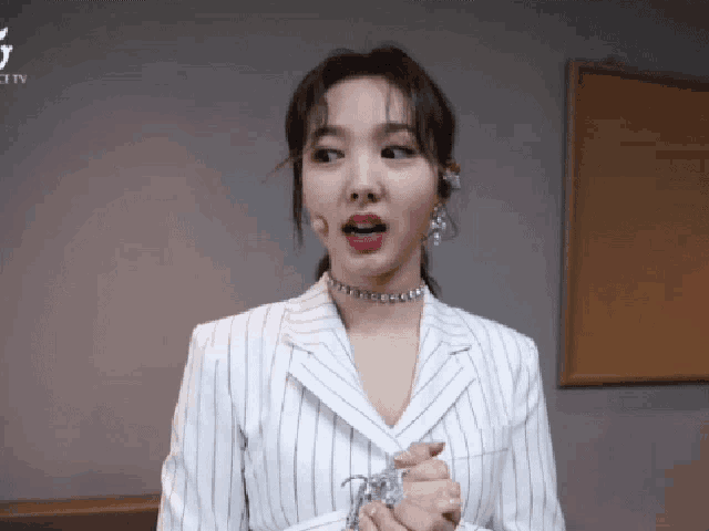 a woman wearing a striped jacket and a choker is standing in front of a sign that says twice tv